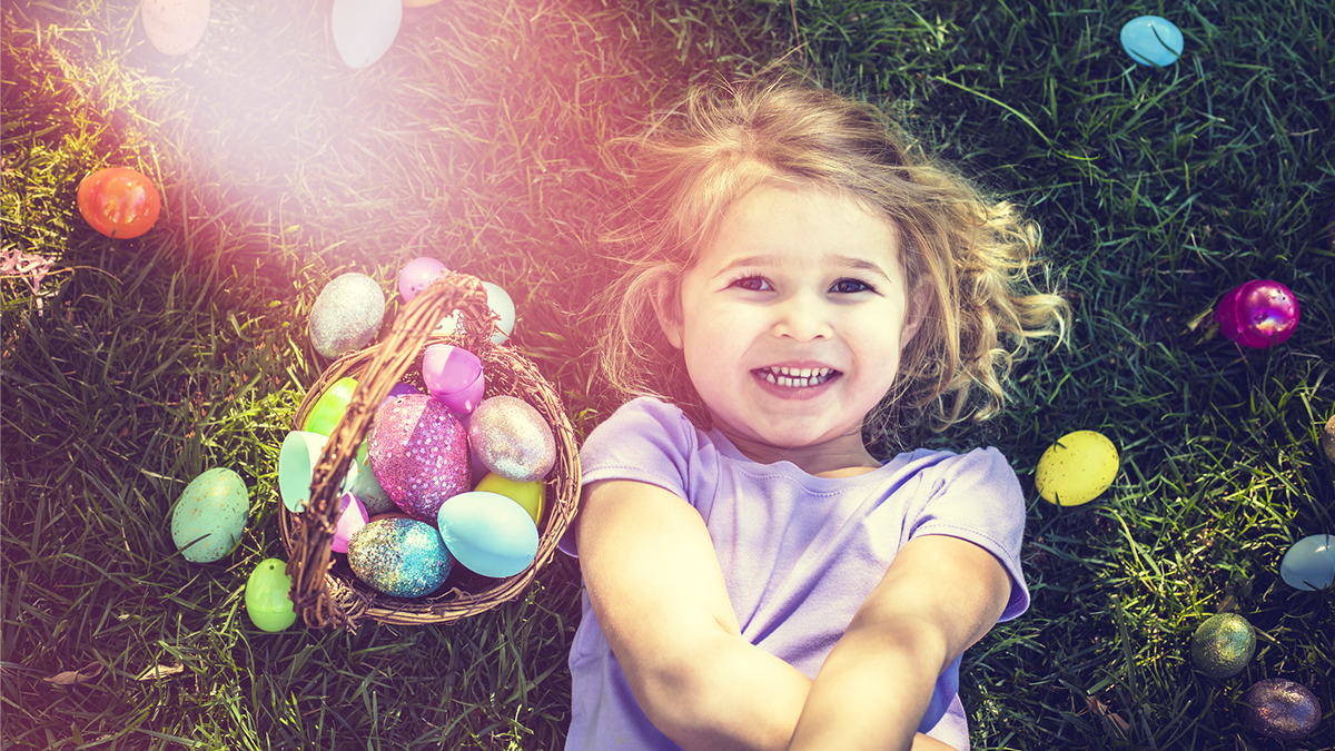 child laying on the ground surrounded by easter eggs and an easter basket